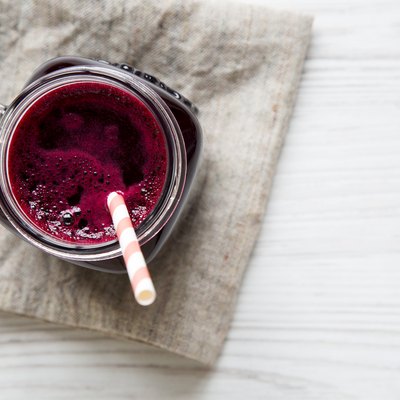 Glass jar of beetroot smoothie, top view. White wooden background. From above, overhead, flat lay. Copy space.