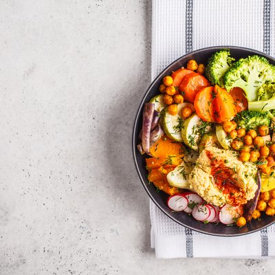 Vegan Buddha bowl with baked vegetables, chickpeas, hummus and tofu, top view.