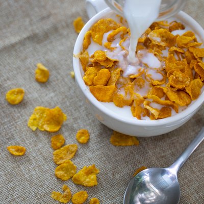 Close-Up Of Milk Being Poured In Corn Flakes On Table