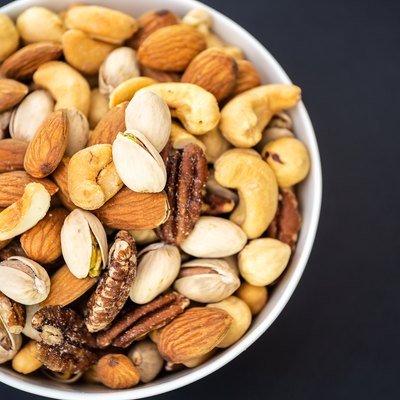 Mixed nuts in a white bowl on a black background.