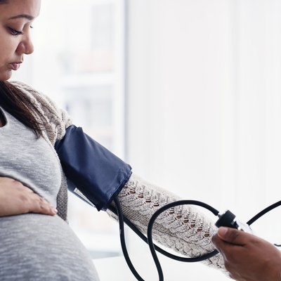 A pregnant woman getting her blood pressure taken by a doctor