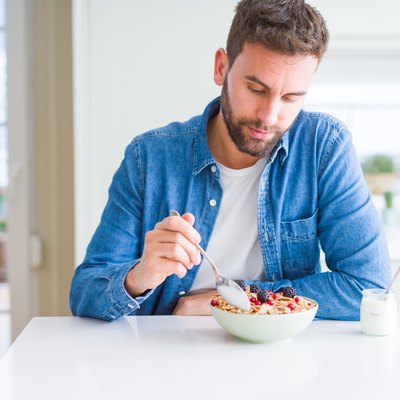 Handsome man having breakfast eating cereals at home and smiling