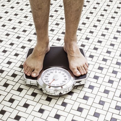 Adult man who takes Metformin standing on bathroom scales.