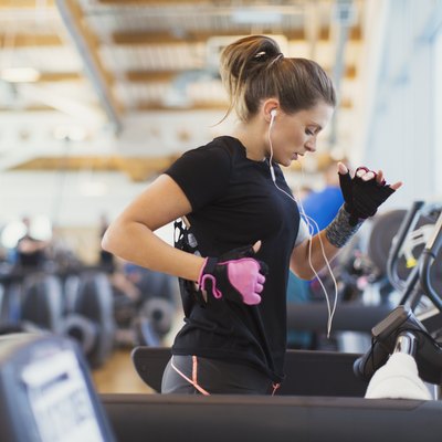 Woman running on treadmill at gym with headphones