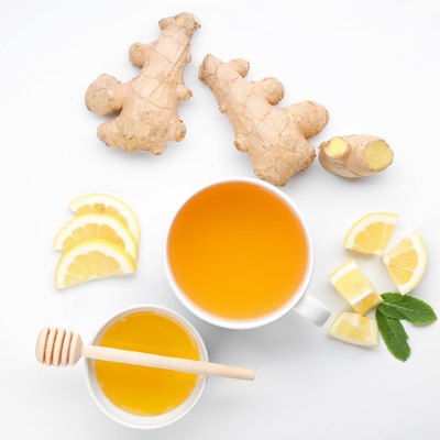 Cup of delicious tea with ginger, lemon and honey on white background