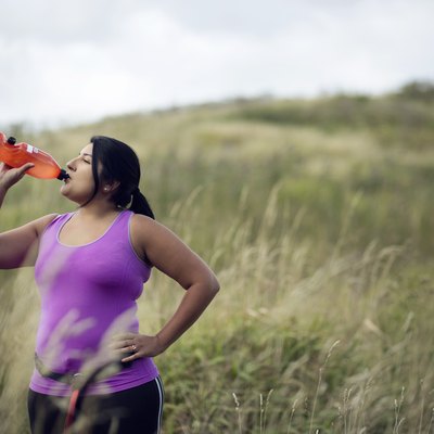 Female jogger drinking diet supplements like Plexus from bottle
