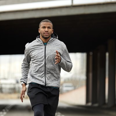 Portrait of young athlete jogging on road in city