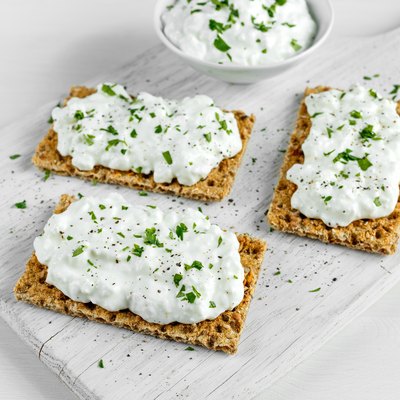 Homemade Crispbread toast with Cottage Cheese and parsley on white wooden board.