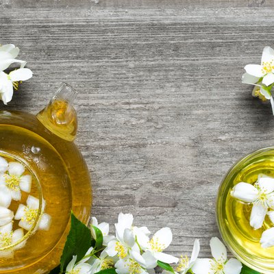 Cup of green herbal tea with jasmine flowers and teapot