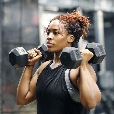 Fit, young African American woman working out with hand weights in a fitness gym.