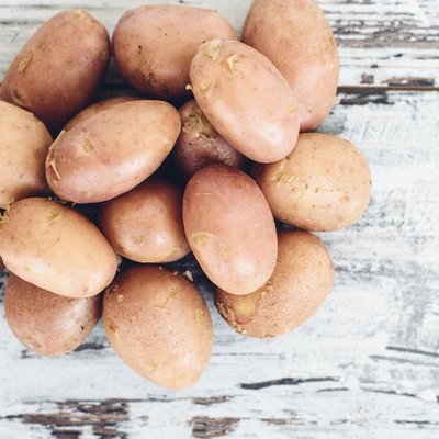 Тew potatoes on vintage wooden table top view