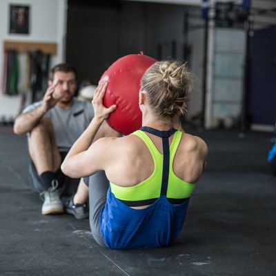 Adults doing ab workouts together with a medicine ball