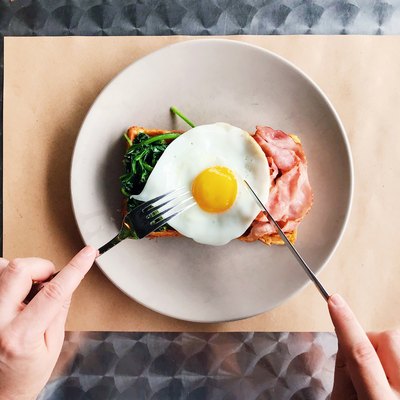 Eating breakfast with Belgian waffle, bacon, spinach and fried egg, personal perspective view