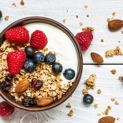 bowl of oat granola with yogurt, fresh raspberries, blueberries
