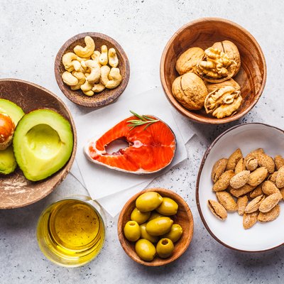 Top view of a variety of foods with healthy fats, including fish, nuts, oil, olives and avocado