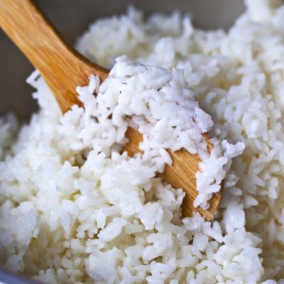 Rice in pot being stirred with wooden spoon
