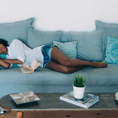 A young black woman taking a nap on a blue sofa