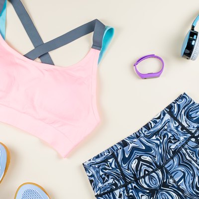 Woman sport bra, leggins, sneakers, headphones and fitness tracker on neutral background. Sport fashion concept.