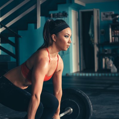 Woman crouching to lift barbell in gym