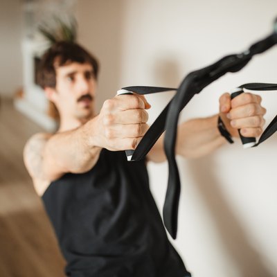 adult man practicing suspension training at modern home