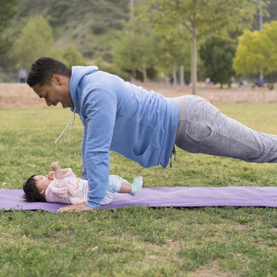 Father exercising with baby in park, enjoying the benefits of a strong core
