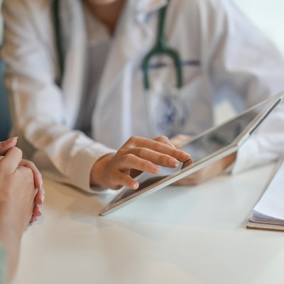 Doctor showing a patient some information on a digital tablet about effects of chemotherapy on the liver