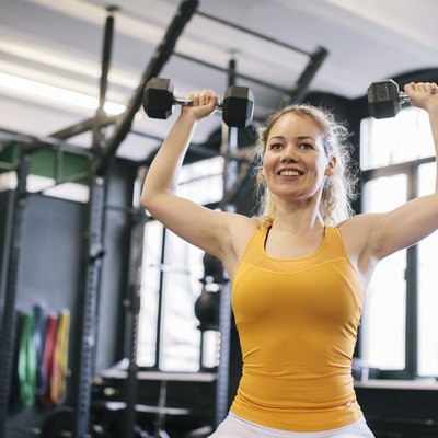 Young Woman Doing Dumbbell Exercises in Gym