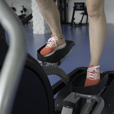 Woman's feet on cross-trainer at gym