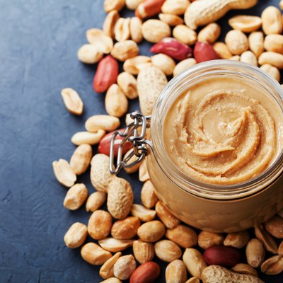 Peanut butter jar and heap of nuts on vintage table with copy space for text.