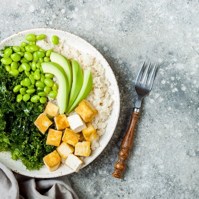 Cauliflower rice Buddha bowl with massaged kale, tofu, avocado and edamame beans. Vegan poke bowl