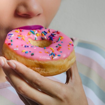 A woman eating a doughnut who has a sugar craving caused by gut problems
