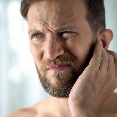 A man suffering from aching ears and a headache