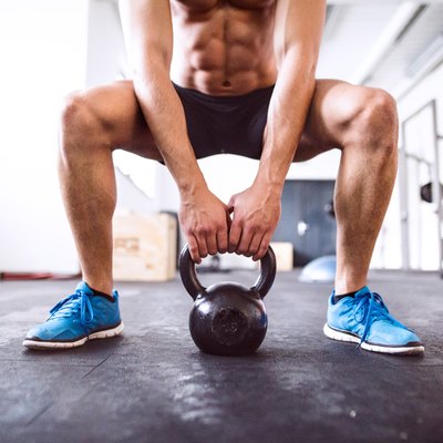 Unrecognizable fit hispanic man in gym working out with kettlebell