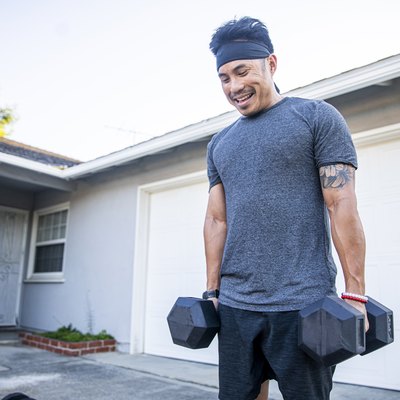 Filipino man working out with dumbbells outside to build muscle
