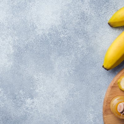 Banana and sliced banana into pieces with honey on textured background, copy space.