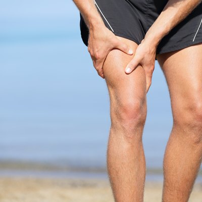 A waist-down view of a man holding his front thigh in pain