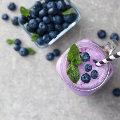 Mason jar of tasty blueberry smoothie on light table