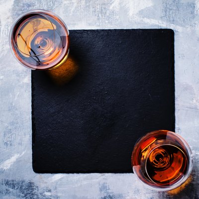 Cognac in two glasses on stone background, top view