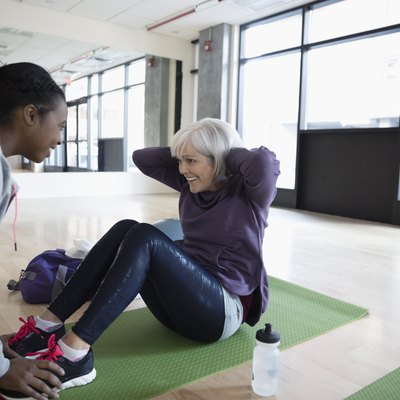Personal trainer encouraging woman doing beginner HIIT workout at the gym