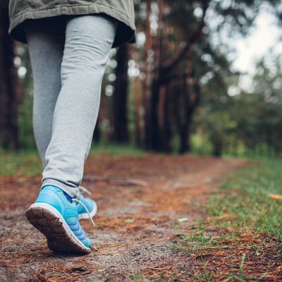 Woman tourist walking in spring forest. Close up of shoes. Traveling and tourism concept