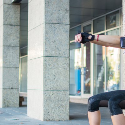 Young sporty girl doing wall sitting exercise urban outdoors.