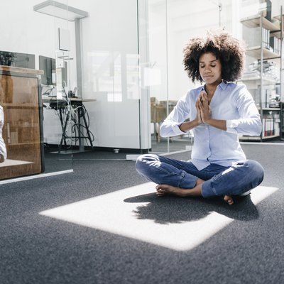 Young woman doing yoga in office