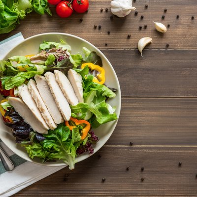 Healthy fresh vegetable salad with skinless boiled chicken breast, top view