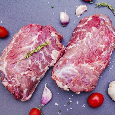 Raw beef meat. Animal protein with dry spiced, rosemary, garlic clove, sea salt and tomato cherry