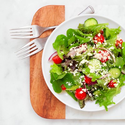 Mixed salad top view on a marble and wood serving board