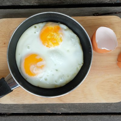 Directly Above Shot Of Fried Egg In Frying Pan On Cutting Board Over Table