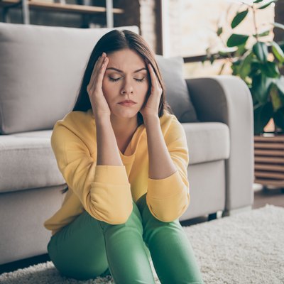 Close up photo of frustrated ill girl sit floor suffer headache migraine pain have health problems close eyes in house living room