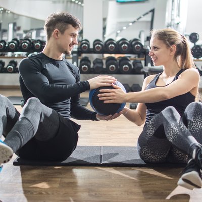 Sporty fitness couple doing abdominal exercises with medicine ball in the gym.