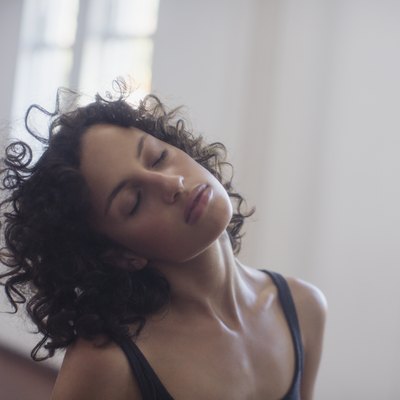 Calm young female dancer stretching neck in dance studio