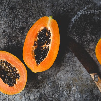 Directly Above Shot Of Halved Papaya Slices And Knife On Table